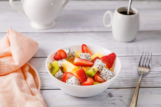 Fruit salad of pineapple, strawberries, kiwi and pitahaya in a white plate. High quality photo