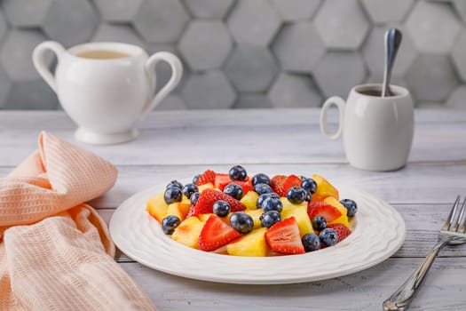 Fruit salad with pineapple, strawberries and blueberries on a white plate. High quality photo