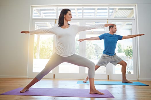 Practicing yoga together. Full length shot of a mature couple practicing yoga in their home