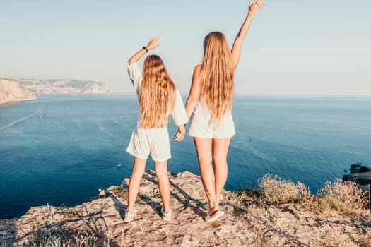 Close up portrait of mom and her teenage daughter hugging and smiling together over sunset sea view. Beautiful woman relaxing with her child.