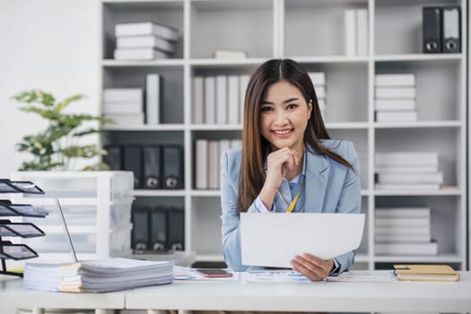 Smile Pretty business Asian woman is working her job on a laptop computer in a modern office. Doing accounting analysis report real estate investment data, Financial and tax systems concept...