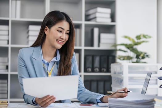 Smile Pretty business Asian woman is working her job on a laptop computer in a modern office. Doing accounting analysis report real estate investment data, Financial and tax systems concept...