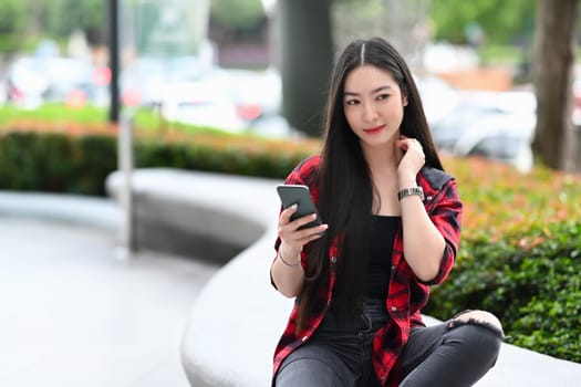 Beautiful Asian woman using mobile at outdoor.