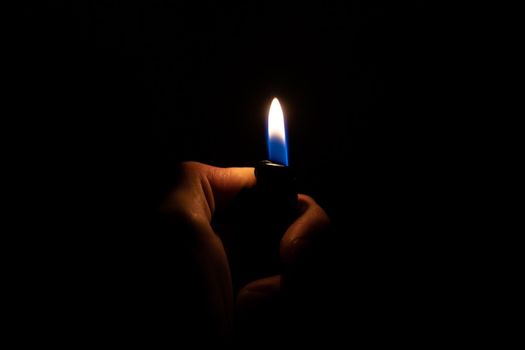 Burning lighter in hand in the dark close up