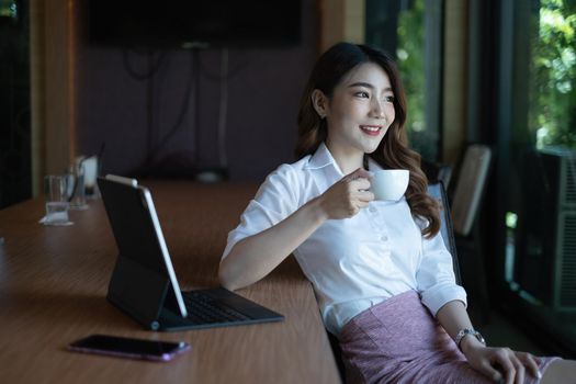 Businesswoman working to analyze technical price graph and indicator holding cup of coffee at morning