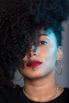 Vertical close-up portrait of beautiful young woman with hair to her face. Studio portrait.