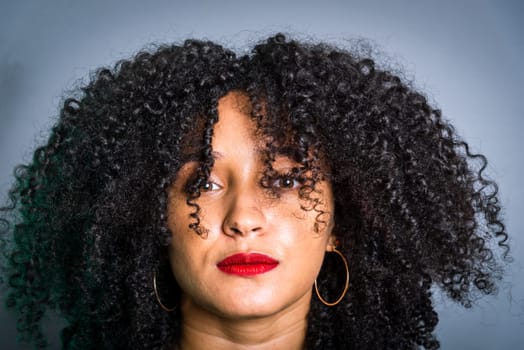 Vertical close-up portrait of beautiful young woman with hair to her face. Studio portrait.