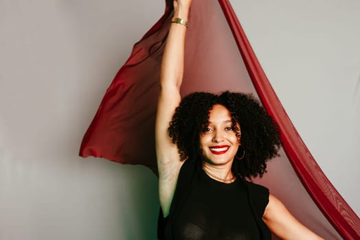 Beautiful young woman with red cloth suspended around her body. studio portrait