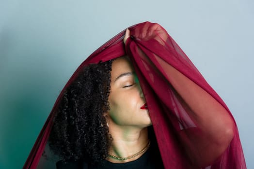 Beautiful young woman with red cloth suspended around her body. studio portrait