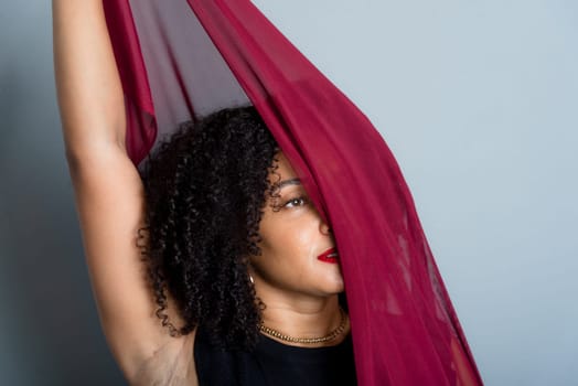 Beautiful young woman with red cloth suspended around her body. studio portrait