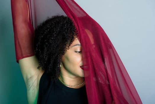 Beautiful young woman with red cloth suspended around her body. studio portrait