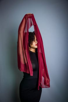 Beautiful young woman with red cloth suspended around her body. studio portrait