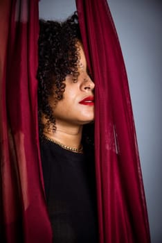 Beautiful young woman with red cloth suspended around her body. studio portrait