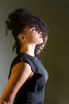 Beautiful young woman in profile wearing black clothing, with hair in her face. Studio portrait.