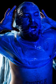 Man with plastic bag over his head, suffocated. Studio shot with blue filter. Isolated on black background.