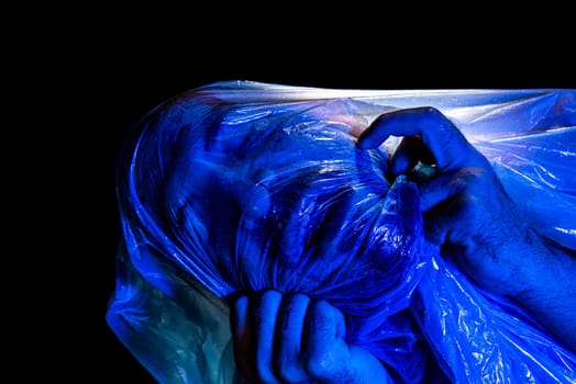 Man with plastic bag over his head, suffocated. Studio shot with blue filter. Isolated on black background.