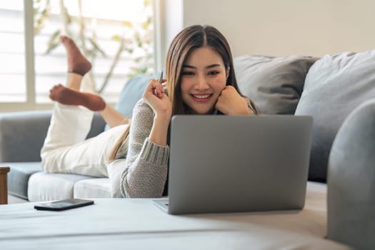 Young woman relaxing using laptop computer on a cold winter day in the bedroom. woman checking social apps and working. Communication and technology concept.