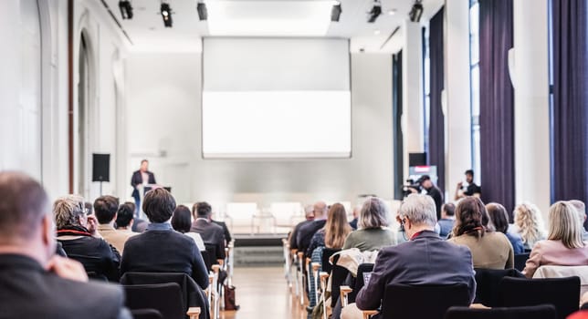 Speaker giving a talk in conference hall at business event. Rear view of unrecognizable people in audience at the conference hall. Business and entrepreneurship concept