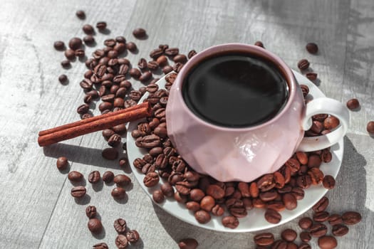 ccup of coffee on the plate with cinnamon on table and coffee beans around