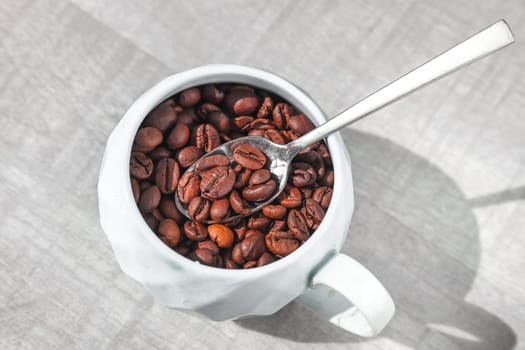 coffee beans in cup on the plate with spoon on the tabe