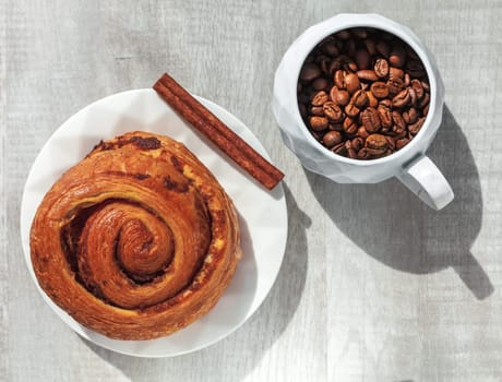 cake on plate cinnamon stick and cup of coffee beans on the table