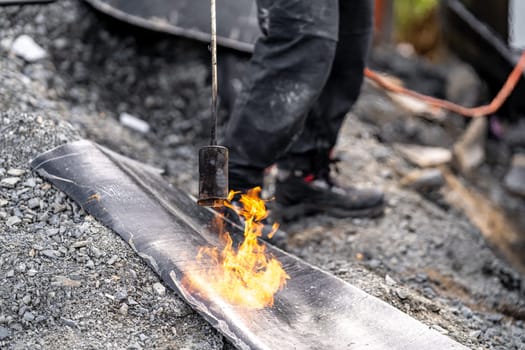 heating the insulation with an open fire. applying asphalt strips to the wall for waterproofing the building. construction of a family house.