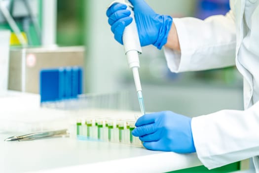 pipetting a sample into a glass beaker during research in a scientific laboratory.