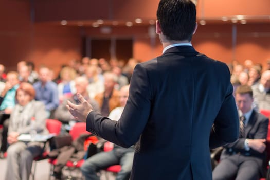 Speaker giving a talk on corporate business conference. Unrecognizable people in audience at conference hall. Business and Entrepreneurship event.