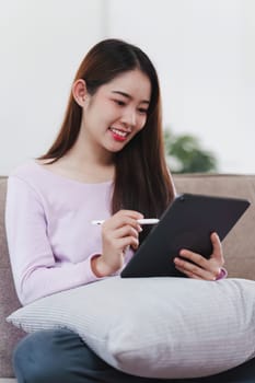 Attractive Asian woman resting comfortable living room and using digital tablet, Relax, Sofa, Lifestyle.