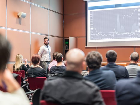 Public Speaker Giving a Talk at Business Meeting. Audience in the conference hall. Skilled coach answers questions of participants of business training. Business and Entrepreneurship concept.