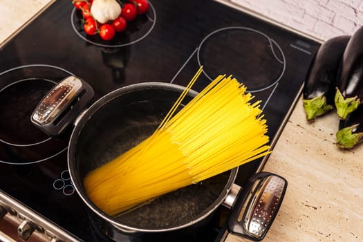 Cooking Italian spaghetti in the kitchen. the concept of Italian cuisine. lifestyle. eggplant, tomatoes and garlic. Ingredients for cooking a vegetarian dinner. household chores