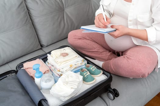 Pregnant woman writing packing list for maternity hospital at home