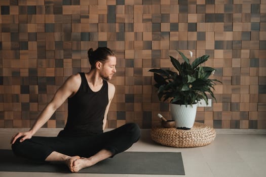 A man performing gymnastic exercises on a yoga mat at home.