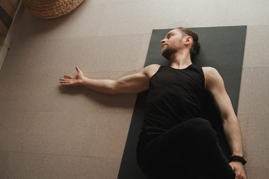 A man performing gymnastic exercises on a yoga mat at home.