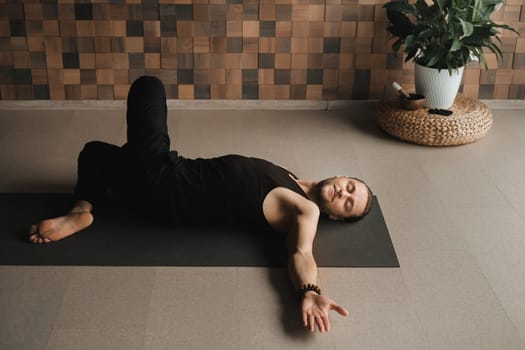 A man performing gymnastic exercises on a yoga mat at home.