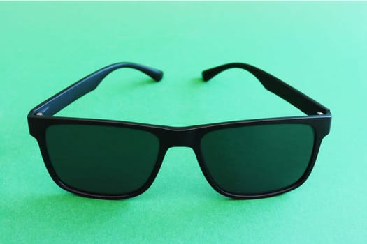 Fashion summer concept. Copy space. Black trendy generic sunglasses on a green paper background.....