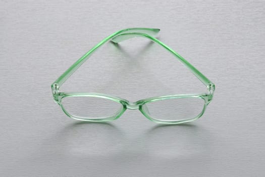 Plastic glasses with a green frame on a light gray background...Fashion summer concept. Copy space. vision improvement,