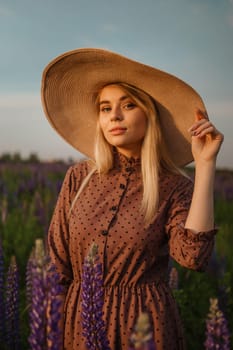 A beautiful woman in a straw hat walks in a field with purple flowers. A walk in nature in the lupin field.