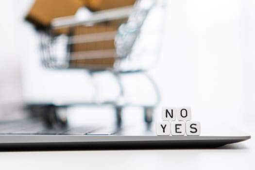 Yes or no words on cubes with a toy shopping cart and cardboard boxes in the background