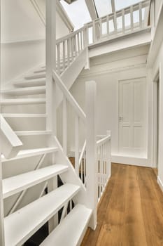 a white house with wood floors and stairs leading up to the second floor in an open living room on a sunny day