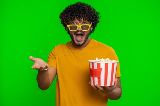 Excited indian man in 3D glasses eating popcorn, watching interesting tv serial, sport game, film, online social media movie content. Hindu guy enjoying domestic entertainment on chroma key background