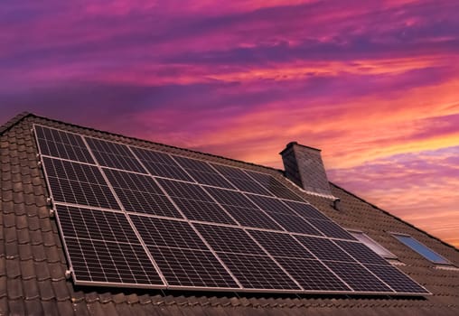 Solar panels producing clean energy on a roof of a residential house during sunset