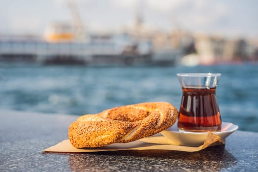 A glass of Turkish tea and bagel Simit against golden horn bay in Istanbul, Turkey. Turkiye.