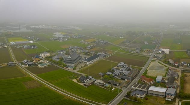 Aerial view of buildings and roads under low fog in Japanese countryside. High quality photo