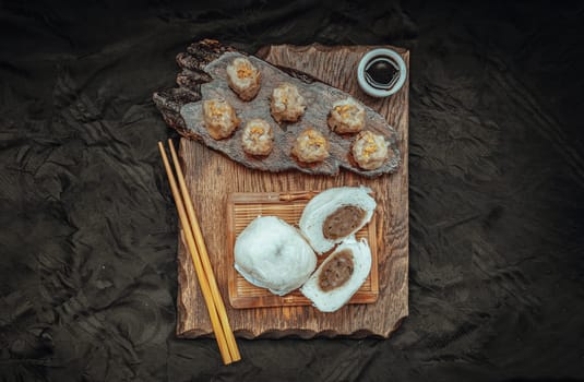 Steamed buns with minced pork filling and Pork shumai or Chinese steamed dumpling served with sour sauce and wooden chopstick. Chinese Dim Sum. Top view, Space for text, Selective Focus.