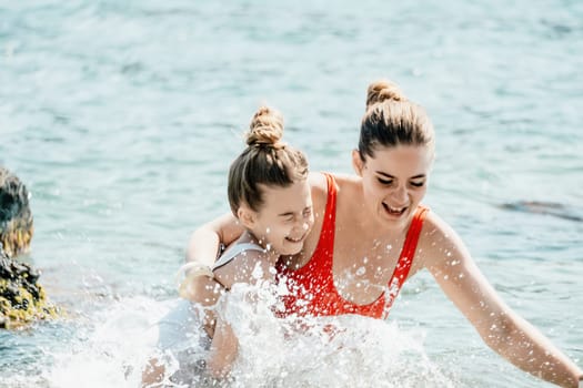 Woman and her daughter together on rock in the sea.