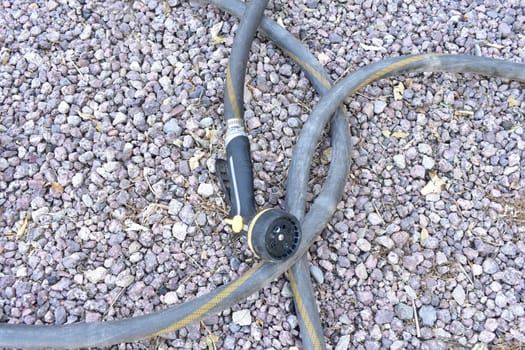 Garden Hose Sprayer Laying in Rocky Yard . High quality photo