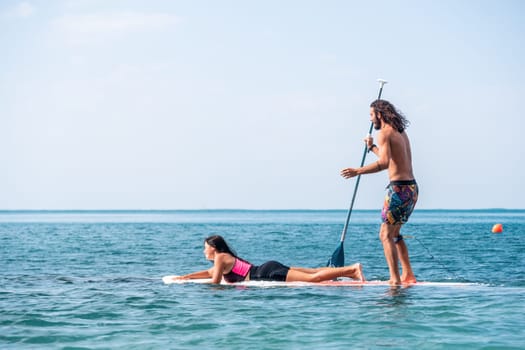 Silhouette of woman standing, surfing on SUP board, confident paddling through water surface. Idyllic sunset or sunrise. Sports active lifestyle at sea or river.