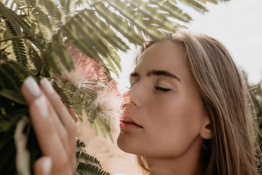 Beauty portrait of young woman closeup. Young girl smelling Chinese acacia pink blossoming flowers. Portrait of young woman in blooming spring, summer garden. Romantic vibe. Female and nature.