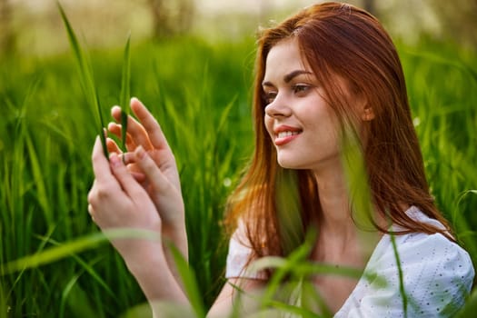 portrait of a cute woman sitting in the grass and smiling joyfully looking at the leaves. High quality photo